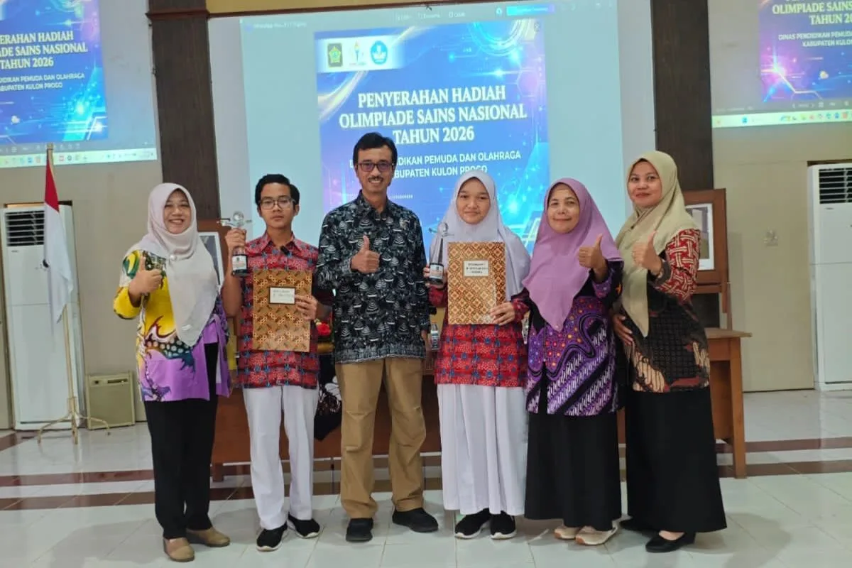 Kenzie (kiri, baju merah) dan Yessie (kanan, baju merah), dua siswa SMPN 2 Sentolo yang sabet juara OSN SMP Kabupaten 2026 bersama Kepala Dinas Dikpora Kabupaten Kulon Progo, Drs. Nur Wahyudi, M.M (tengah) dan para guru. (Dok Dikpora Kulon Progo)